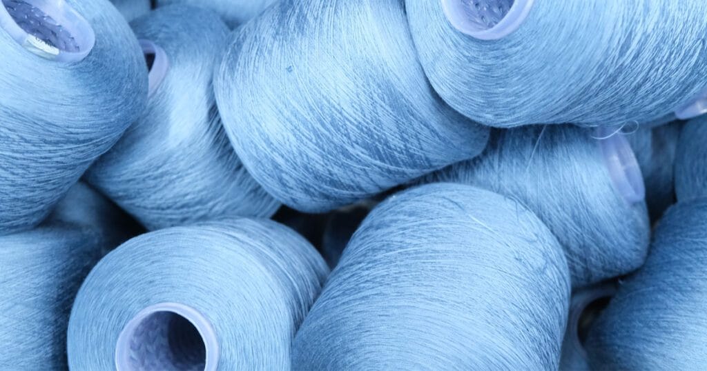 Blue yarn cones representing Dyecon’s advanced thread dyeing technology and denim innovation.