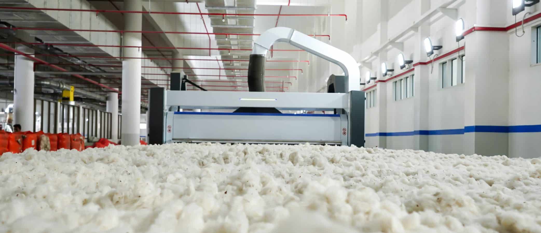 Cotton fibers moving through advanced processing machinery inside AGI Denim’s textile facility.